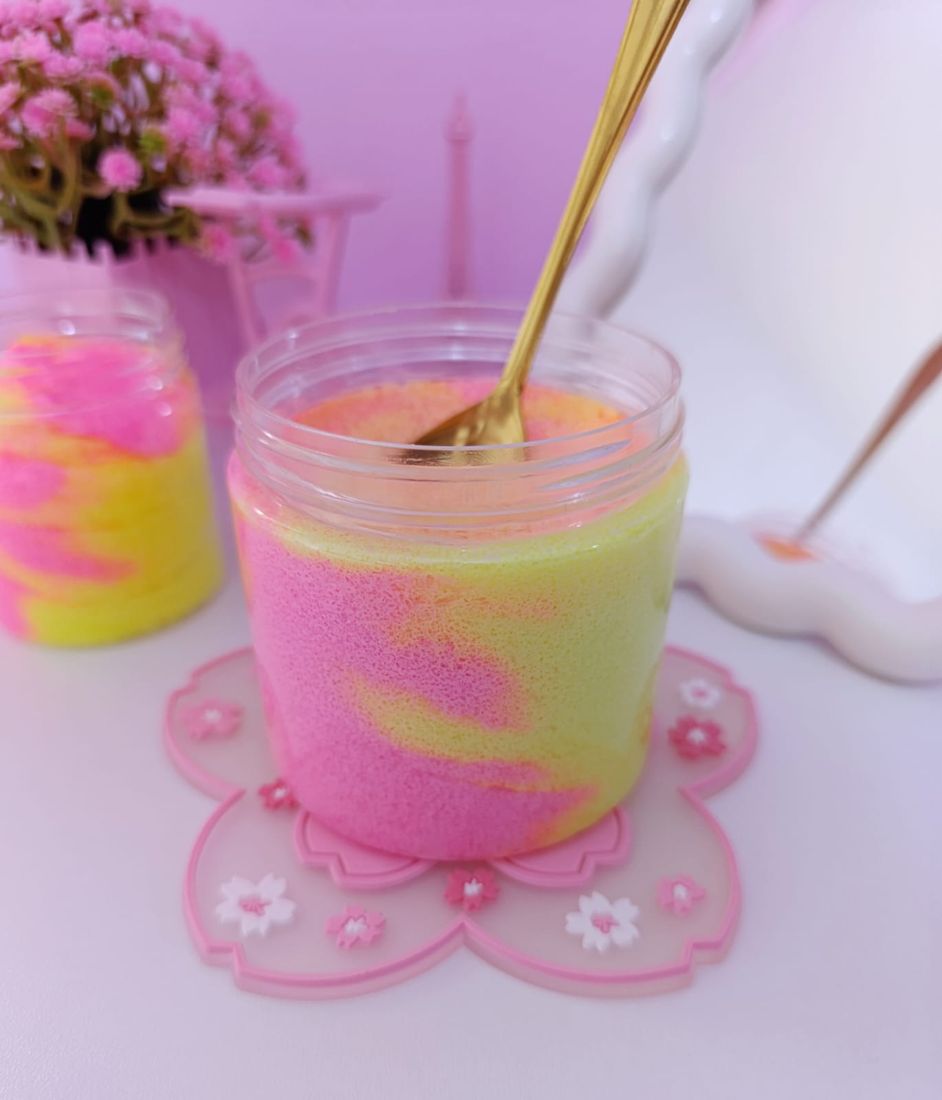 Exfoliante batido rosa y amarillo en un frasco con cuchara dorada